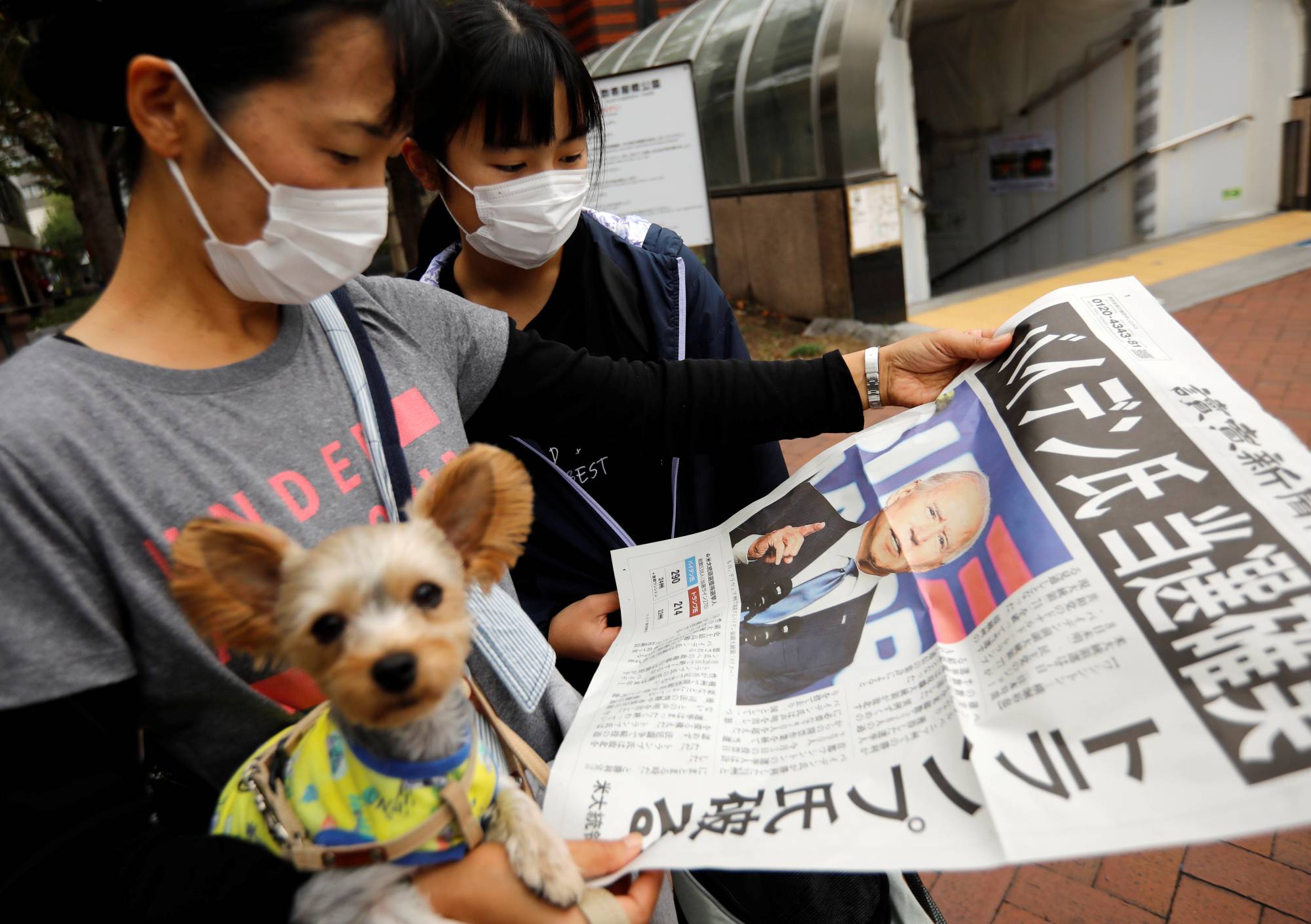 People read an extra edition of a newspaper reporting that Democratic U.S. presidential nominee Joe Biden is projected to win the 2020 U.S. presidential election in Tokyo on Sunday. | REUTERS
