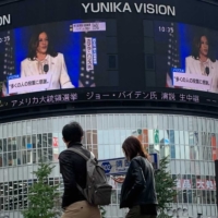 People watch Vice President-elect Kamala Harris speak in Wilmington, Delaware, on a screen Sunday in Shinjuku Ward, Tokyo. | AP