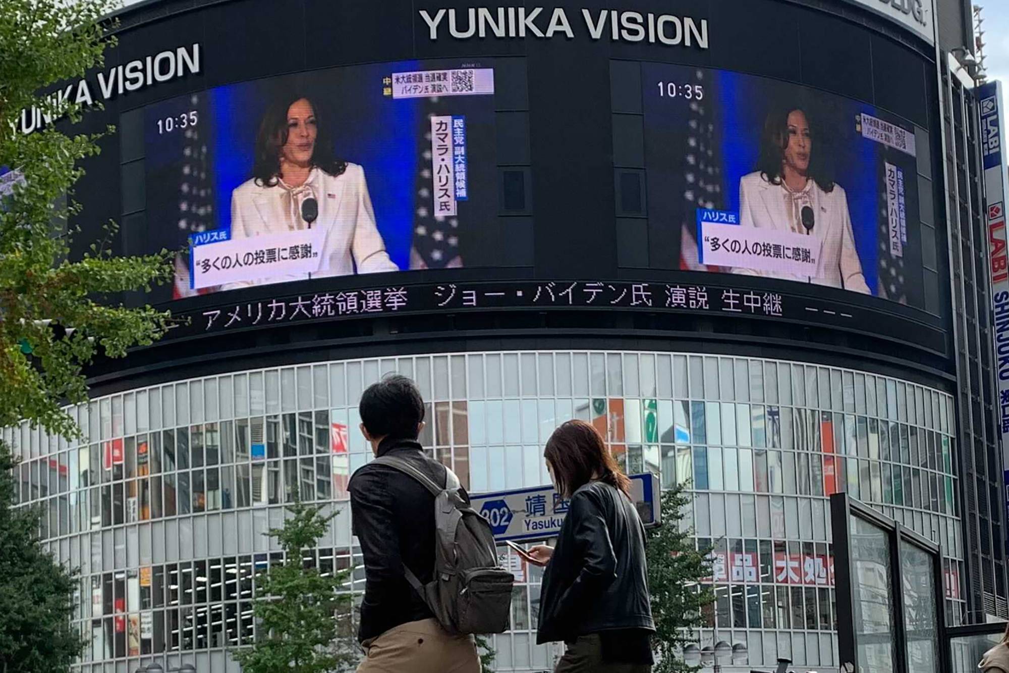 People watch Vice President-elect Kamala Harris speak in Wilmington, Delaware, on a screen Sunday in Shinjuku Ward, Tokyo. | AP