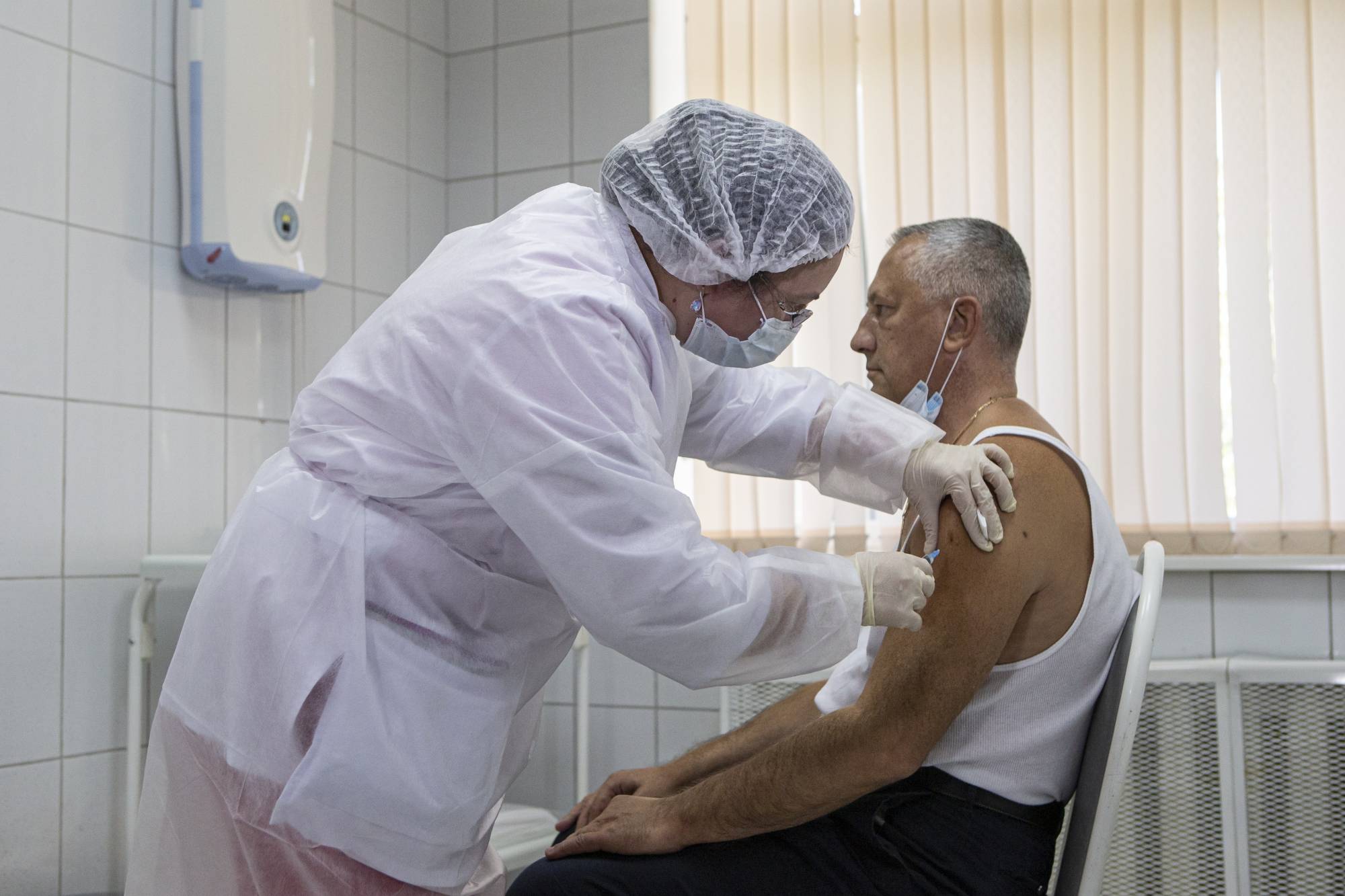 A medical worker administers a shot of Russia's experimental Sputnik V coronavirus vaccine in Moscow. | AP
