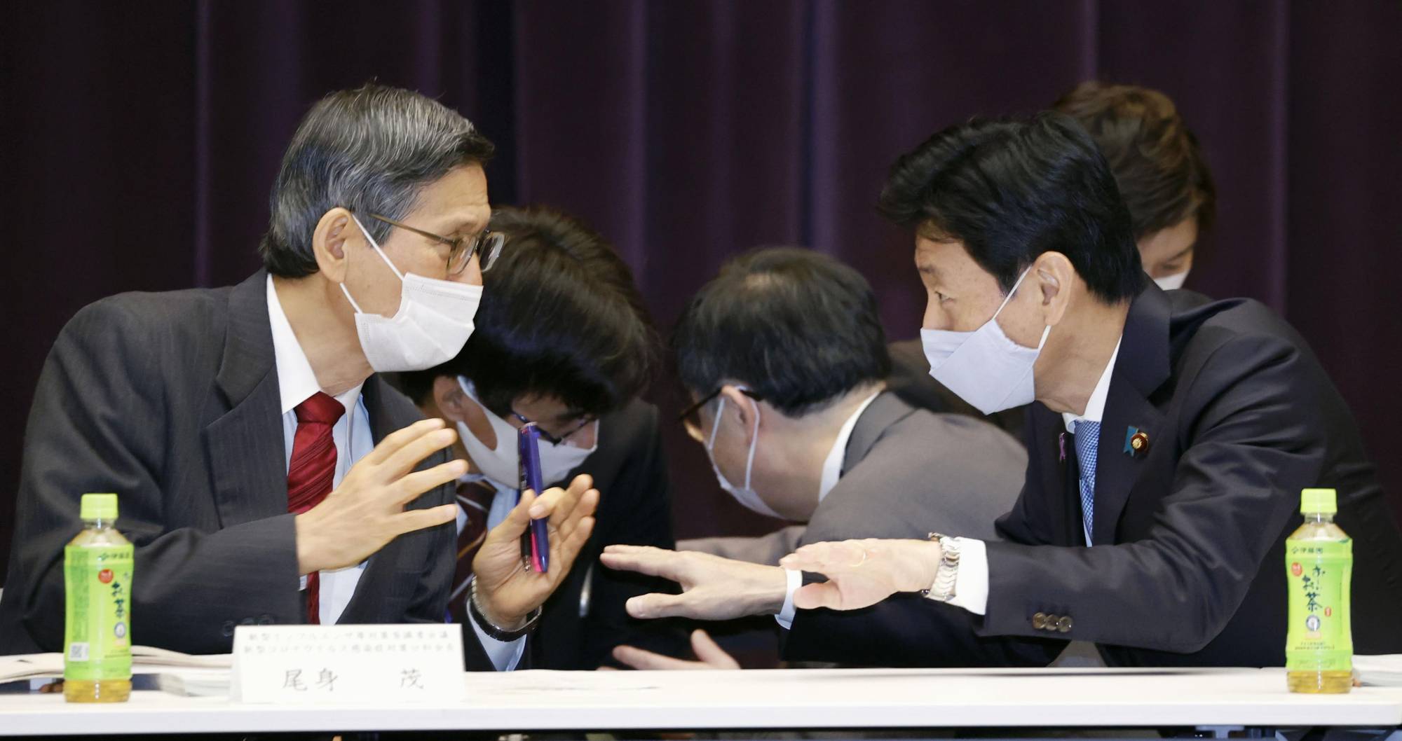 Yasutoshi Nishimura, the minister in charge of Japan's COVID-19 response (right), talks with Shigeru Omi, head of the coronavirus government panel, at the panel's meeting in Tokyo on Thursday. | KYODO