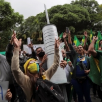 Demonstrators carry a giant syringe as they protest against Sinovac\'s potential COVID-19 vaccine in Sao Paulo on Nov. 1. | REUTERS
