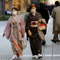 Women wearing kimono and masks walk in Tokyo on Friday. | REUTERS