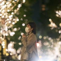 A woman walks down a street decorated with seasonal lighting in Tokyo on Thursday. | AP
