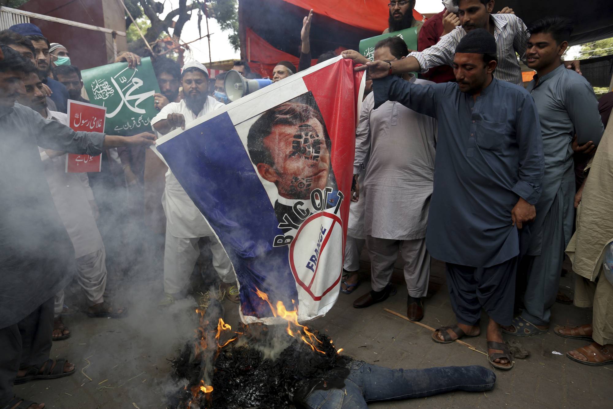 Supporters of Jamaat-e-Islami, a religious political party, burn a representation of a French flag with a defaced image of French President Emmanuel Macron during a protest in Karachi, Pakistan, on Friday. | AP