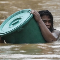 A man uses a plastic canister to float while negotiating rising floodwaters from Typhoon Vamco in Marikina, Philippines, on Thursday.  | AP