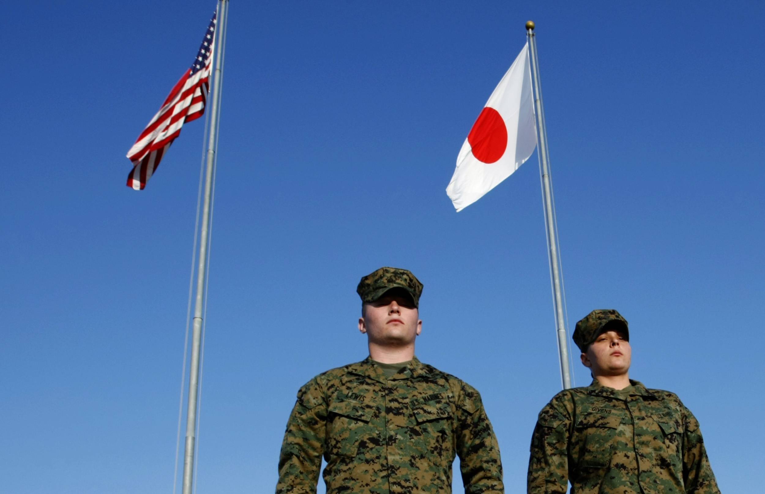 U.S. Marines walk past the U.S. and Japanese national flags at Marine headquarters at Camp Foster in Ginowan, Okinawa, in March 2008. The September 1995 rape of an Okinawan school girl fundamentally changed the fabric of U.S.-Japan-Okinawa relations afterward. | REUTERS 
