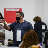 A challenger raises his hand for additional review while officials count absentee ballots in Detroit on Nov. 4. | BRITTANY GREESON / THE NEW YORK TIMES