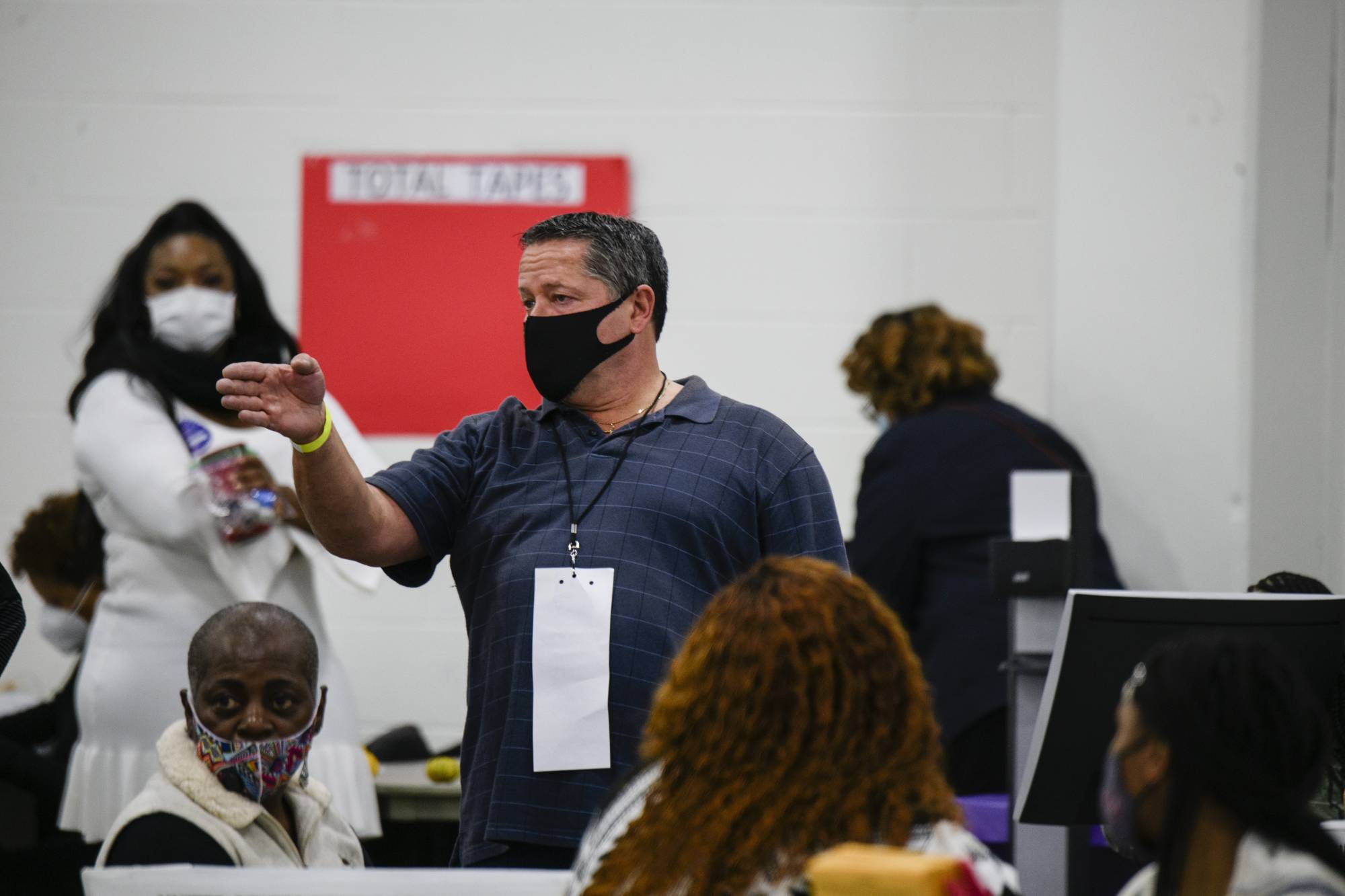 A challenger raises his hand for additional review while officials count absentee ballots in Detroit on Nov. 4. | Brittany Greeson / The New York Times