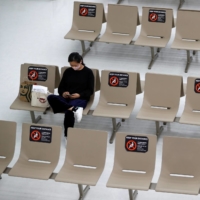 Signs requesting social distancing are displayed on seats in the arrival zone of Narita International Airport, where there are fewer passengers than usual amid the COVID-19 pandemic, in Chiba Prefecture on Nov. 2. | REUTERS