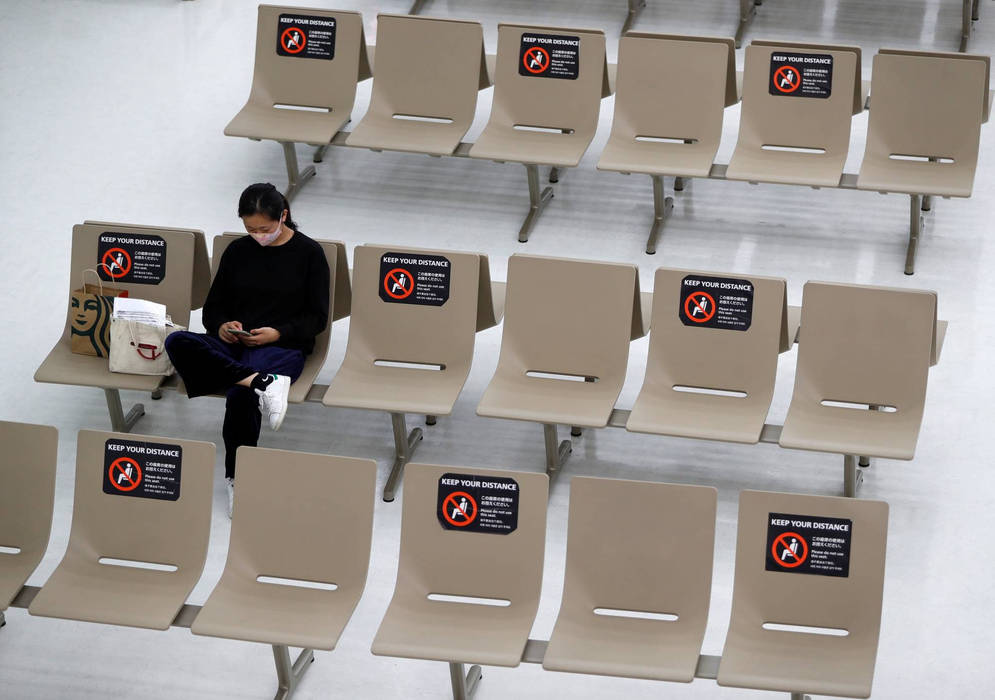 Signs requesting social distancing are displayed on seats in the arrival zone of Narita International Airport, where there are fewer passengers than usual amid the COVID-19 pandemic, in Chiba Prefecture on Nov. 2. | REUTERS