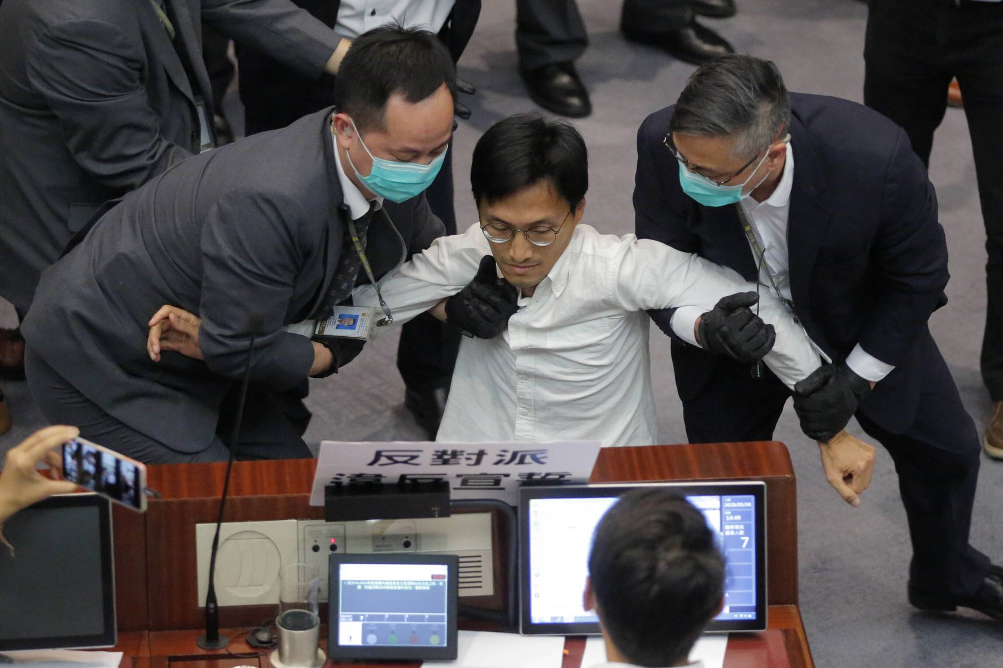 Then-lawmaker Eddie Chu is taken away by security guards during a Legislative Council session in Hong Kong in May. Police arrested Chu and two other former opposition lawmakers on Wednesday.  | AP