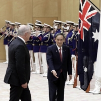 Prime Minister Yoshihide Suga reviews an honor guard with Australian Prime Minister Scott Morrison during a welcoming ceremony in Tokyo on Tuesday. | BLOOMBERG