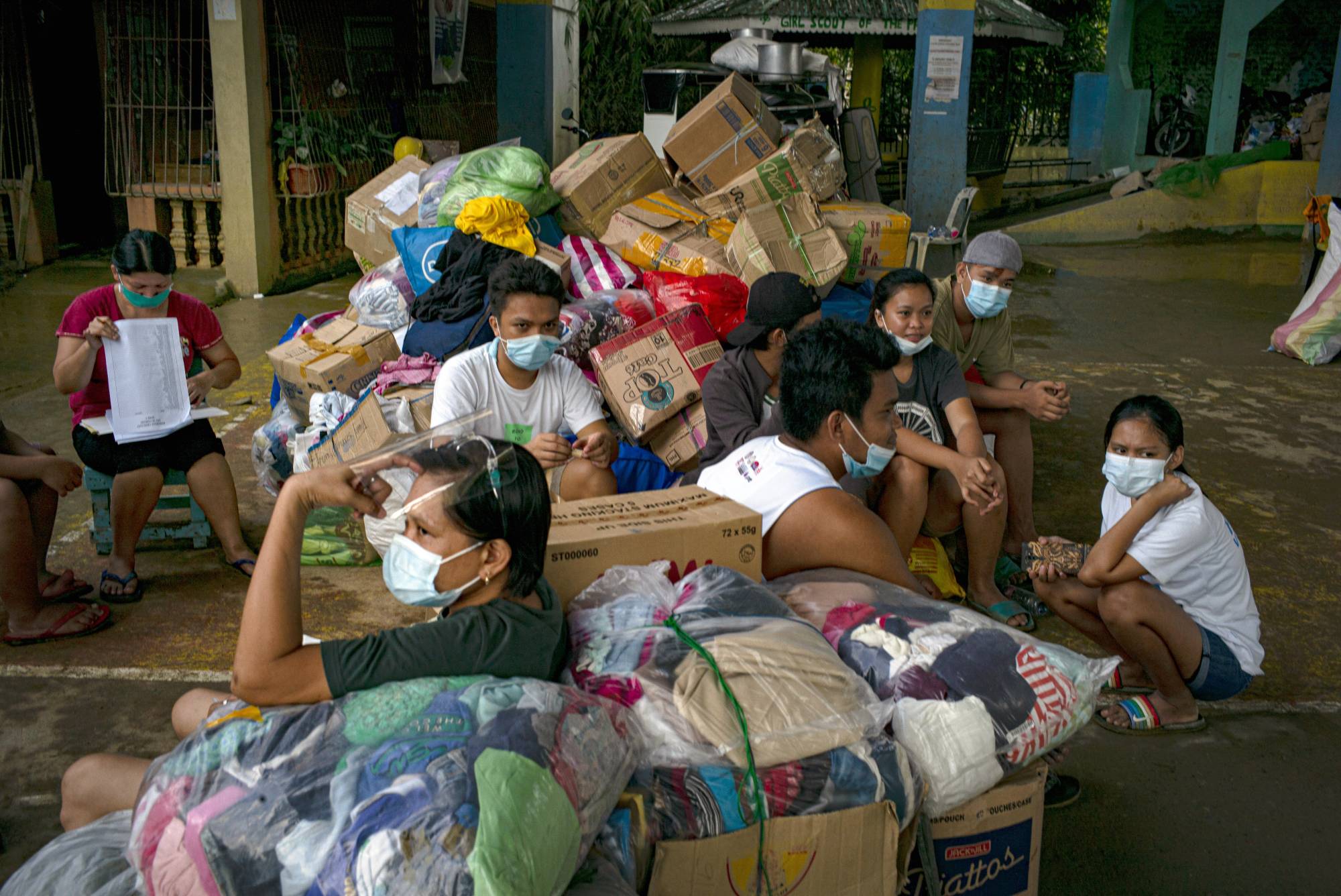 Residents with a pile of relief goods in Tuguegarao City, Cagayan Province, Philippines, on Monday. Torrential rains and back-to-back typhoons have ripped through the country in the past two weeks, turning a once picturesque river into a sea of murky brown, killing dozens and setting off deadly landslides. | JES AZNAR / THE NEW YORK TIMES