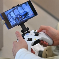 A staff member plays a game using Microsoft\'s Xbox controller at the SK Telecom flagship store in Seoul on November 10. | AFP-JIJI