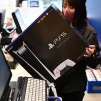 An employee prepares a new Sony PlayStation 5 gaming console for a customer on the first day of its launch on Nov. 12 at an electronics shop in Kawasaki. | AFP-JIJI