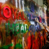 Demonstrators spray-paint a plaque in front of the police headquarters during a rally in Bangkok on Wednesday.  | REUTERS 