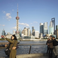 People take selfies of the Pudong skyline as they stand on the Bund in Shanghai on Thursday. | AP