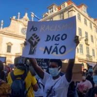 A protester holds a sign reading \"Say no to racism\" during an anti-racism protest in Lisbon in July.  | REUTERS