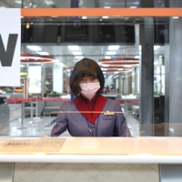 A flight attendant is seen behind a plastic shield amid the coronavirus pandemic at Songshan Airport in Taipei on Thursday.  | REUTERS