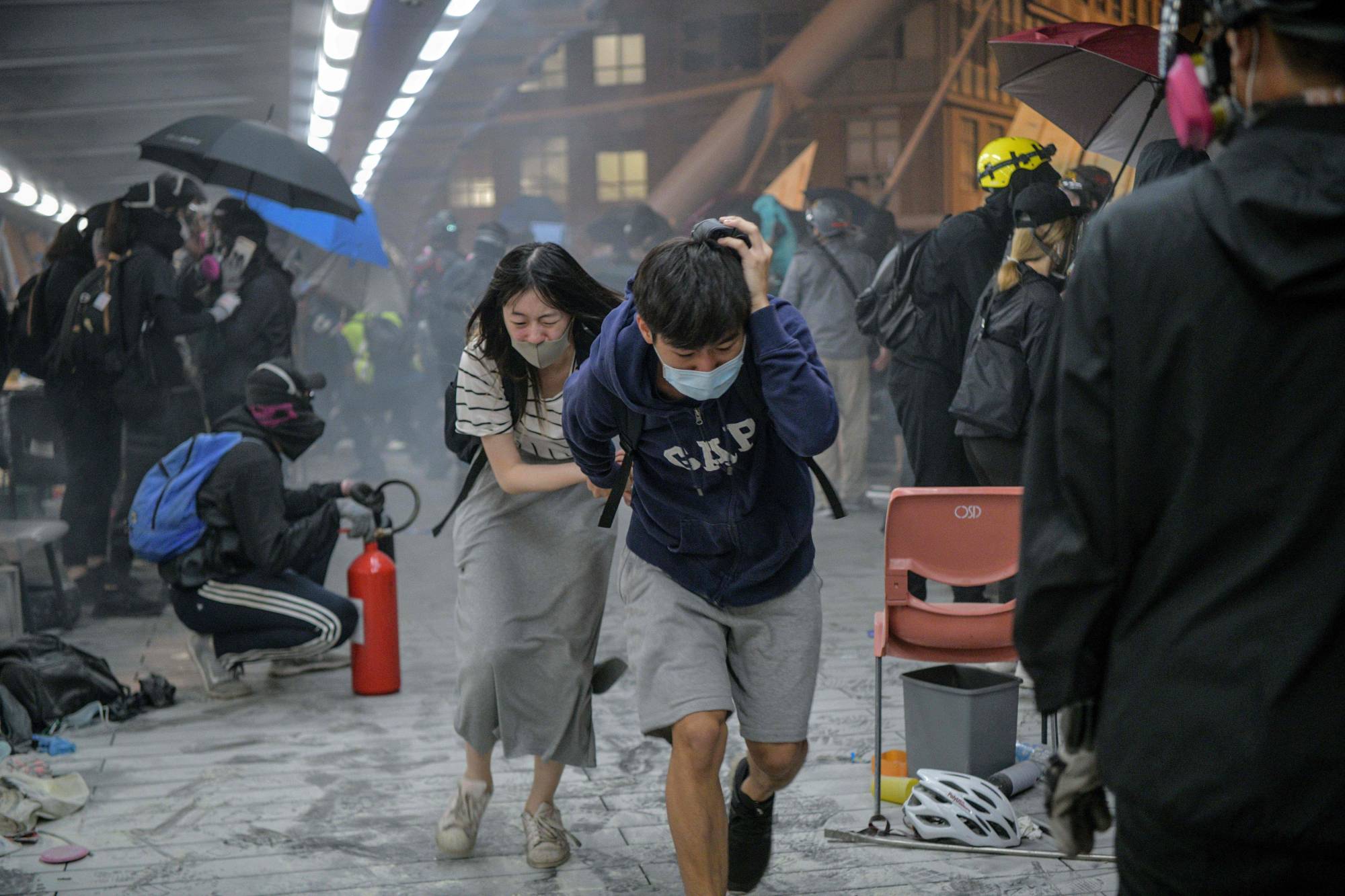 Protesters run for cover after riot police fired tear gas as they tried to escape from the Hong Kong Polytechnic University campus and police in November last year.  | AFP-JIJI