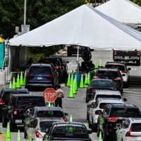 People wait inside vehicles at a drive-through COVID-19 testing site in Miami Beach, Florida, on Nov. 17. | AFP-JIJI