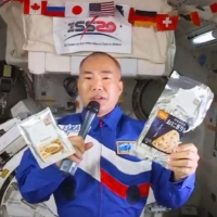 Japanese astronaut Soichi Noguchi holds space food items he brought from Japan to the International Space Station. | KYODO　