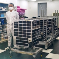 The microsatellite Suisen (front) and three other compact observational satellites are presented to the media in Tokyo on Thursday. | KYODO