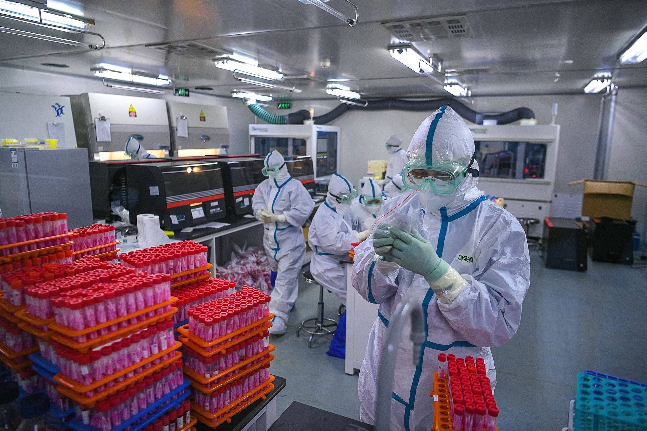 Technicians process COVID-19 coronavirus tests at a laboratory in Tianjin, China. | AFP-JIJI / GETTY IMAGES / VIA BLOOMBERG