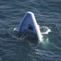 A fishing vessel capsizes on Saturday morning after colliding with a cargo vessel at a port in Ibaraki Prefecture. | KYODO