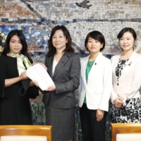 A civic group submits a petition that calls for more female parliamentary representation to ruling party lawmaker Seiko Noda (center) in Tokyo in October. | KYODO