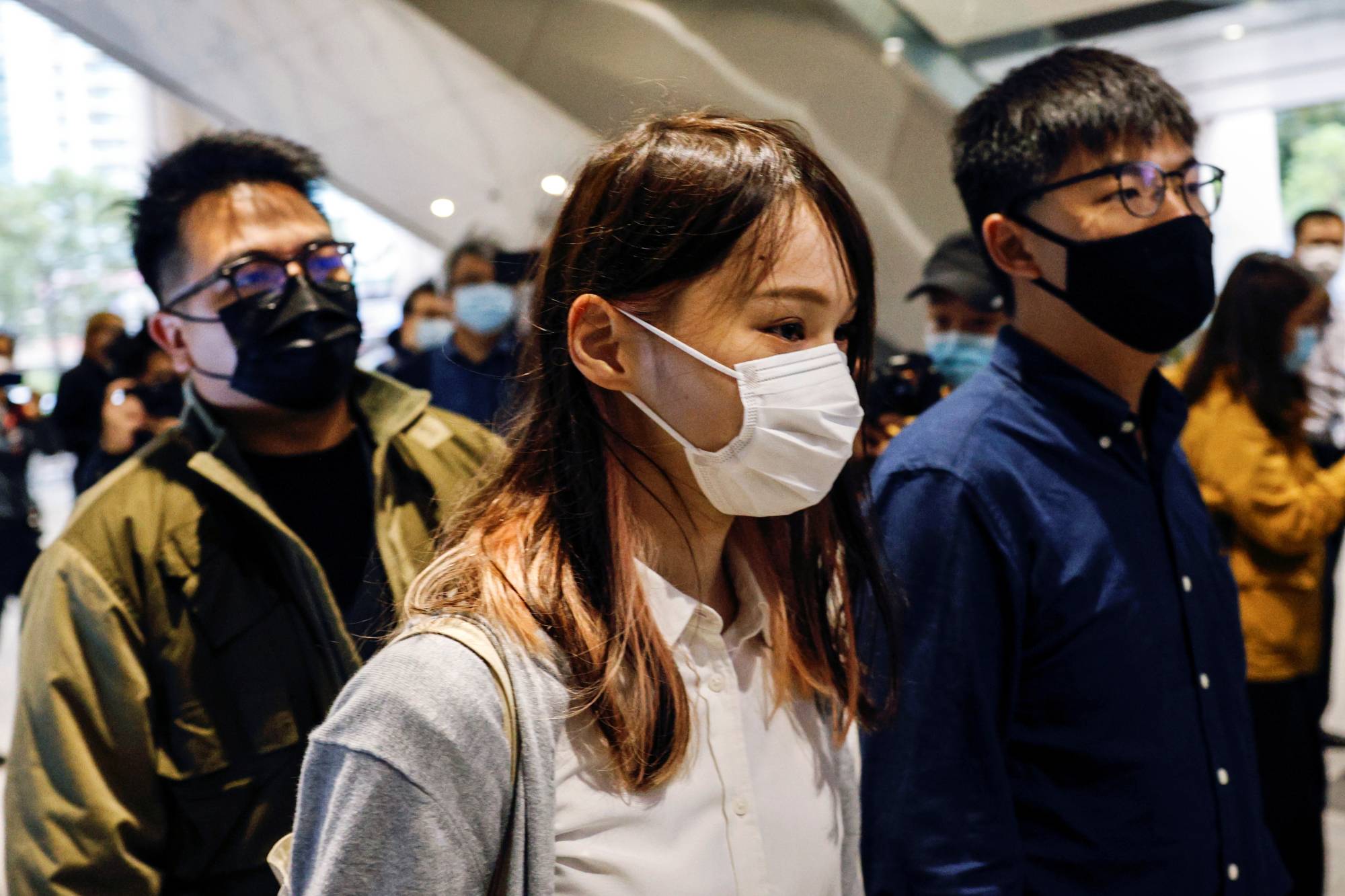 Pro-democracy activists Ivan Lam, Joshua Wong and Agnes Chow arrive at the West Kowloon Magistrates' Courts to face charges related to illegal assembly stemming from 2019, in Hong Kong on Nov. 23. | REUTERS