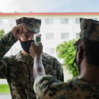 A U.S. Marine conducts a temperature check in front of the dining facility at Camp Courtney in Okinawa Prefecture in July. | U.S. MARINES