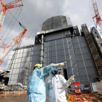 A Tepco employee gives a lecture in front of the No. 3 reactor building at Fukushima No. 1 nuclear power plant in 2019. | REUTERS