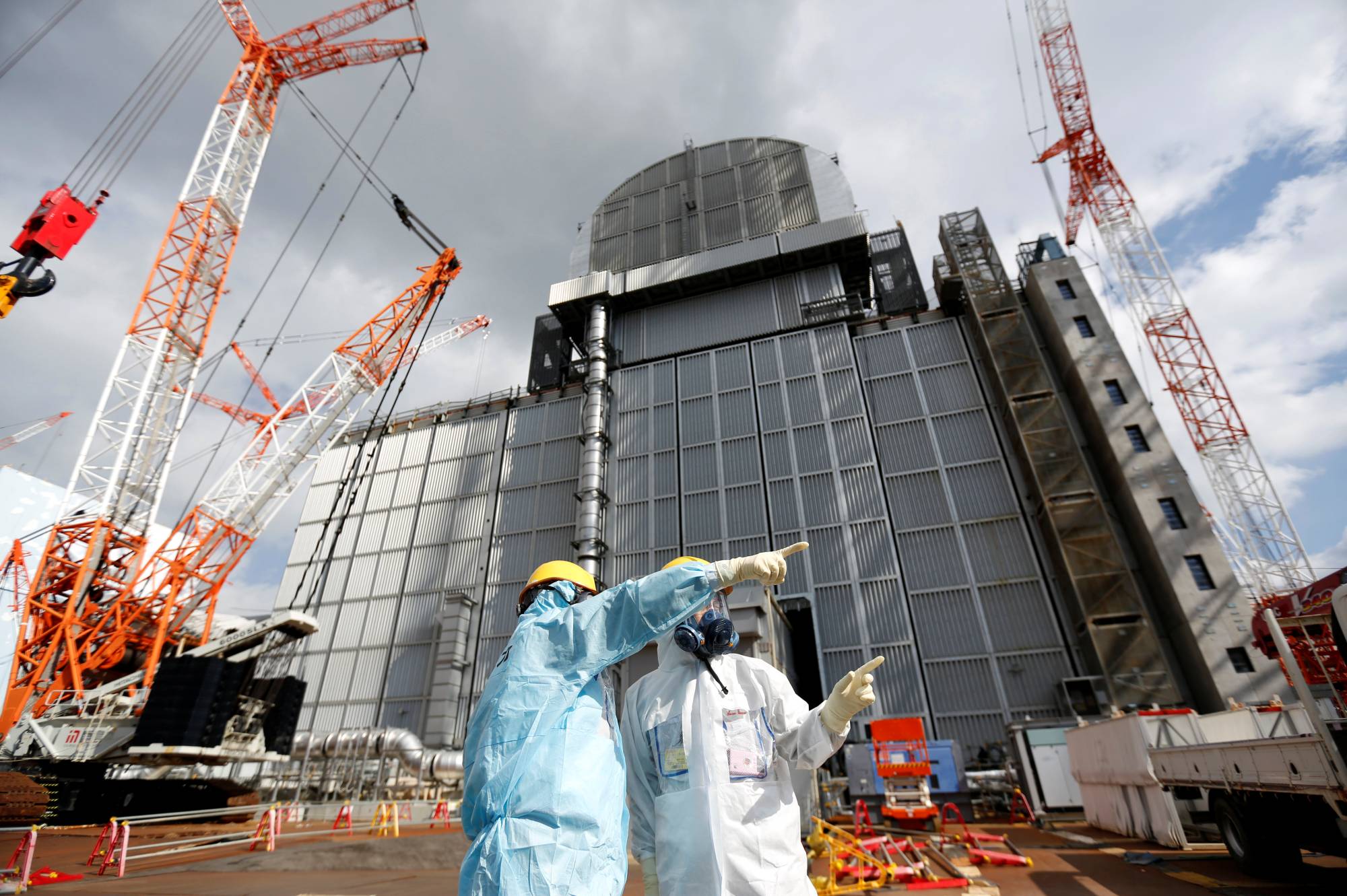 A Tepco employee gives a lecture in front of the No. 3 reactor building at Fukushima No. 1 nuclear power plant in 2019. | Reuters