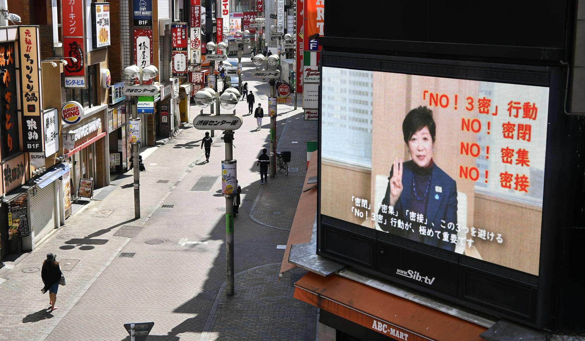 A screen in the Shibuya entertainment district of Tokyo shows Gov. Yuriko Koike asking people to avoid the 'Three Cs' — closed spaces, crowds and close-contact situations — amid the spread of the novel coronavirus in April. | KYODO