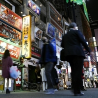 People walk in Tokyo\'s Kabukicho entertainment district on Friday, a day before the metropolitan government began requesting restaurants and other establishments serving alcohol to shorten business hours. | KYODO