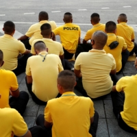 Police officers sit on the ground after the motorcade carrying Thailand\'s King Maha Vajiralongkorn and Queen Suthida drove past in Bangkok in October.  | REUTERS