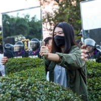 Protesters hold mirrors in front of riot police officers during a pro-democracy rally demanding the prime minister to resign and reforms on the monarchy, in Bangkok on Sunday.  | REUTERS