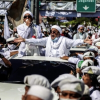 Muslim cleric Rizieq Shihab, leader of the Indonesian hard-line Islamic Defenders Front, greets supporters as he arrives to inaugurate a mosque in Bogor, Indonesia, on Nov. 13. | AFP-JIJI