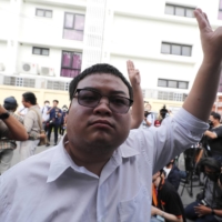 Pro-democracy activist Parit Chiwarak raises a three-finger salute, a symbol of resistance, during a protest in Bangkok on Monday.  | AP