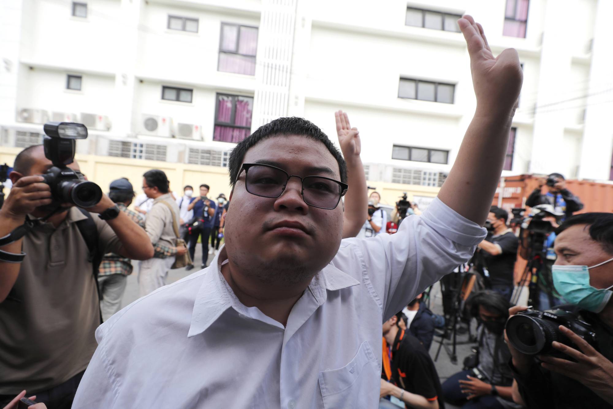 Pro-democracy activist Parit Chiwarak raises a three-finger salute, a symbol of resistance, during a protest in Bangkok on Monday. | AP
