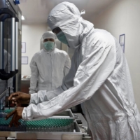 An employee removes vials of AstraZeneca\'s COVID-19 vaccine from a visual inspection machine inside a lab at Serum Institute of India in Pune. | REUTERS