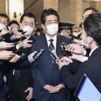 Former Prime Minister Shinzo Abe speaks to reporters in Tokyo on Friday amid allegations that his political group illegally covered shortfalls in the cost of dinners for supporters. | KYODO