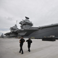 Armed police officers patrol the quayside next to the moored  65,000-ton British aircraft carrier Queen Elizabeth after it arrived at Portsmouth Naval base, its new home port, in Portsmouth, England, on Aug. 16, 2017. | AFP-JIJI
