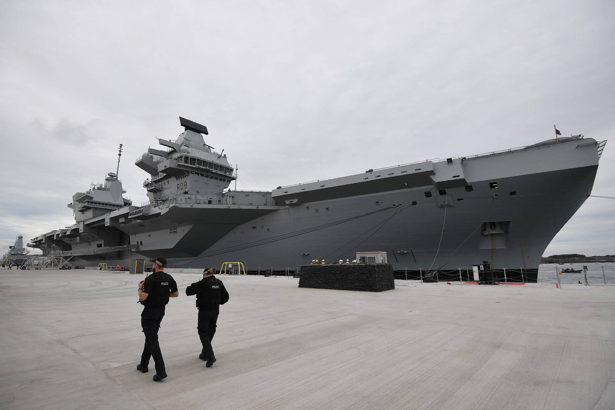 Armed police officers patrol the quayside next to the moored  65,000-ton British aircraft carrier Queen Elizabeth after it arrived at Portsmouth Naval base, its new home port, in Portsmouth, England, on Aug. 16, 2017. | AFP-JIJI