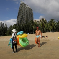 Vendors selling swimming accessories walk on Sanya Bay beach in Sanya, Hainan province, China in November.  | REUTERS 