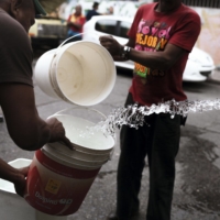 Residents fill buckets during delivery from a water supply truck in Caracas, Venezuela, in 2018.  | BLOOMBERG 