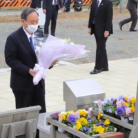 Prime Minister Yoshihide Suga offers flowers at the Ishinomaki Minamihama Tsunami Recovery Memorial Park in Miyagi Prefecture on Thursday. | POOL / VIA KYODO