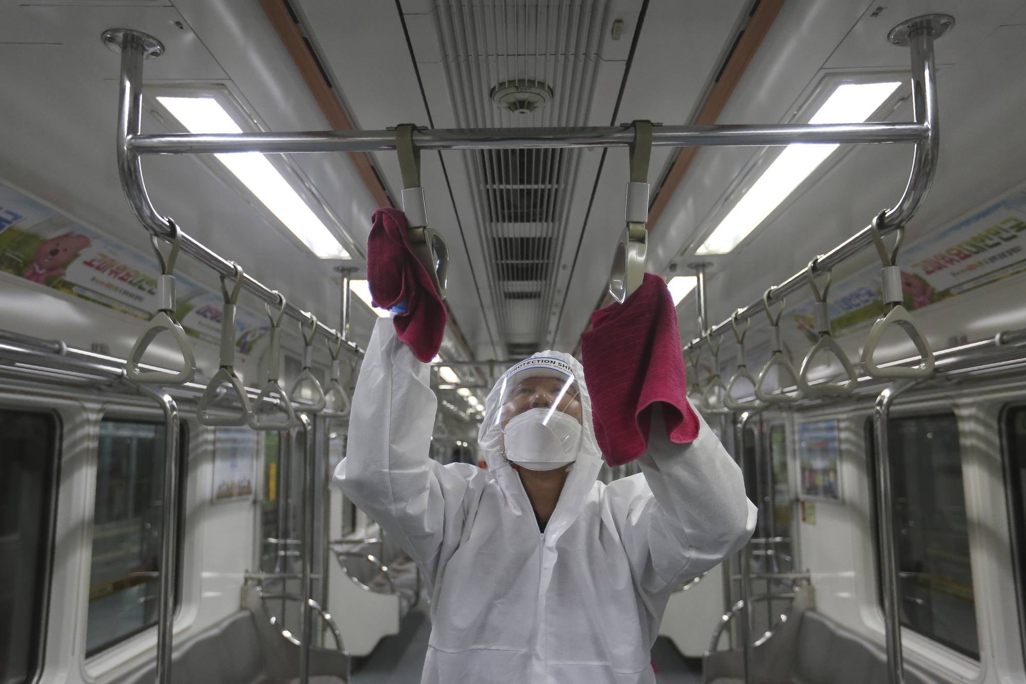 An employee disinfects handles as a precaution against the coronavirus on a subway train in Seoul.  | AP